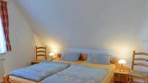 A cozy bedroom with a wooden bed, two bedside lamps, and a window with curtains. - 101 (BC 5) - BUE - Apartment house Hansen (Büsum)