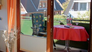 A sliding glass door leading to an outdoor patio with a table, chairs, and a decorative vase. - 101 (BC 5) - BUE - Apartment house Hansen (Büsum)