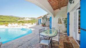 A pool area with a table and chairs, a statue, and blue shutters on a building. - Nice home in Sainte Maxime with WiFi (Sainte Maxime)
