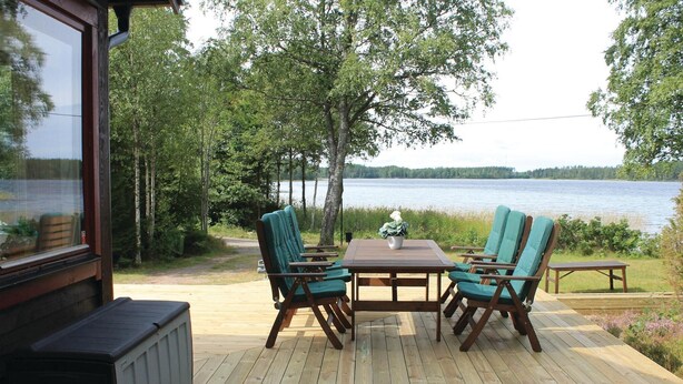 Eine Terrassenausrichtung mit Tisch und Stühlen, mit Blick auf einen See.