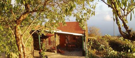 Ein Gebäude aus Stein mit rotem Dach, einer überdachten Terrasse und einem Kiesweg, der zum Eingang führt.