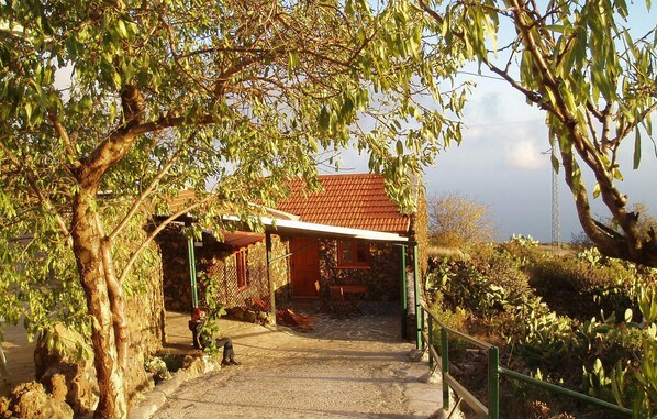 A stone building with a red roof, a covered patio, and a gravel path leading to the entrance. - Beautiful home in Taibique El Hierro (Taibique El Hierro)