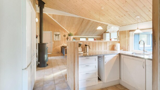 Une cuisine avec des murs en bois, un îlot central et une cuisinière.