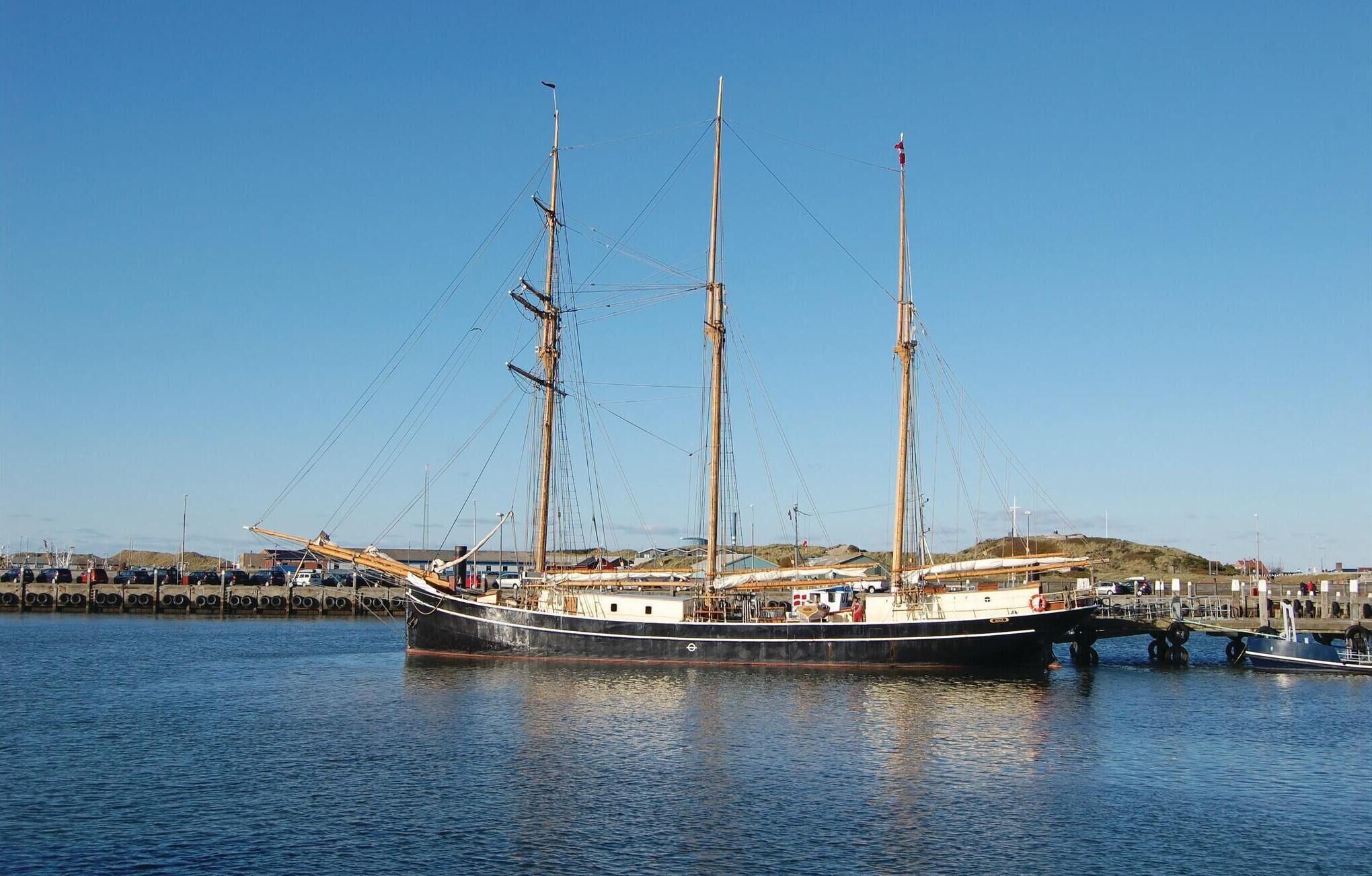 A large sailing ship docked at a harbor with a clear sky.