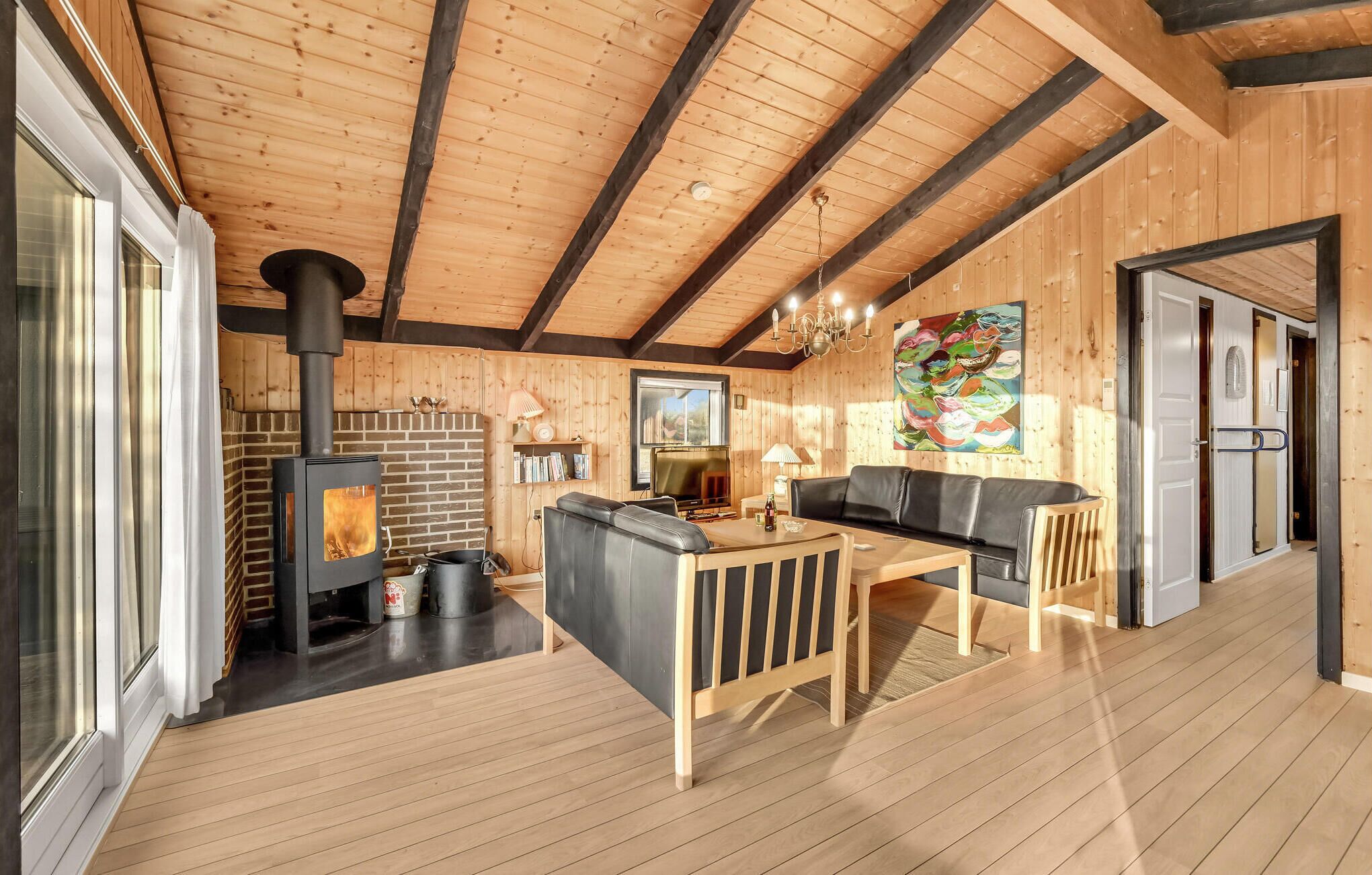 Un intérieur de chalet chaleureux avec une cheminée, des murs en bois, un canapé et un coin repas.