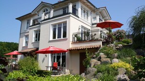 A two-story building with balconies, outdoor seating, and a garden. - Apartment 1 - Villa Amelie (Binz)