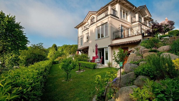 A two-story house with a garden, a patio with outdoor furniture, and a large rock garden. - Apartment 1 - Villa Amelie (Binz)