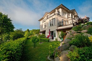 A two-story house with a garden, a patio with outdoor furniture, and a large rock garden.