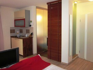 Une chambre d’hôtel équipée d’un lit, d’une télévision, d’une kitchenette et d’une porte coulissante.