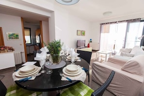 A dining area with a round table set for four, a sofa, a TV, and a window with curtains. - Holiday apartment mit Meerblick (Dramalj)