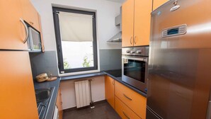 Eine kleine Küche mit einem eingebauten Backofen, einer Mikrowelle und einem Edelstahl-Kühlschrank.