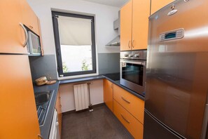 A compact kitchen with a built-in oven, a microwave, and a stainless steel refrigerator. - Holiday apartment mit Meerblick (Dramalj)