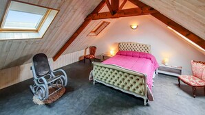 Une chambre à coucher avec un plafond voûté, un lit, une chaise et une table de chevet.