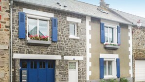 Une maison en pierre à deux étages, avec des volets bleus, une plaque portant le numéro 19 et une porte de garage bleue.