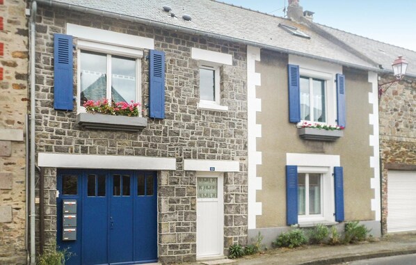 A two-story stone house with blue shutters, a number 19 sign, and a blue garage door.