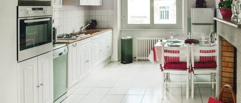 A kitchen with white cabinets, a stove, and a dining area with a table set for four.