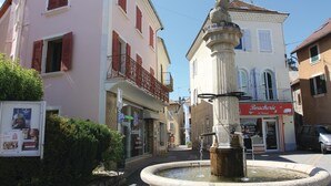 A historic town square with a fountain, a statue, and a shop named 'Boucherie de St. Romain'.