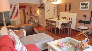 A living room with a sofa, a glass coffee table, and a dining area with a table and chairs.