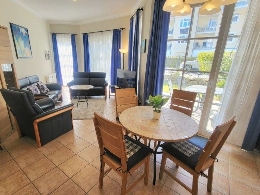 A living room with a sofa, chairs, a coffee table, and a view through large windows.