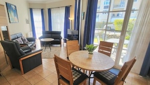 A living room with a sofa, chairs, a coffee table, and a view through large windows. - (49) 3-room apartment with south-facing terrace - Appartementhaus Atlantik (Kühlungsborn)