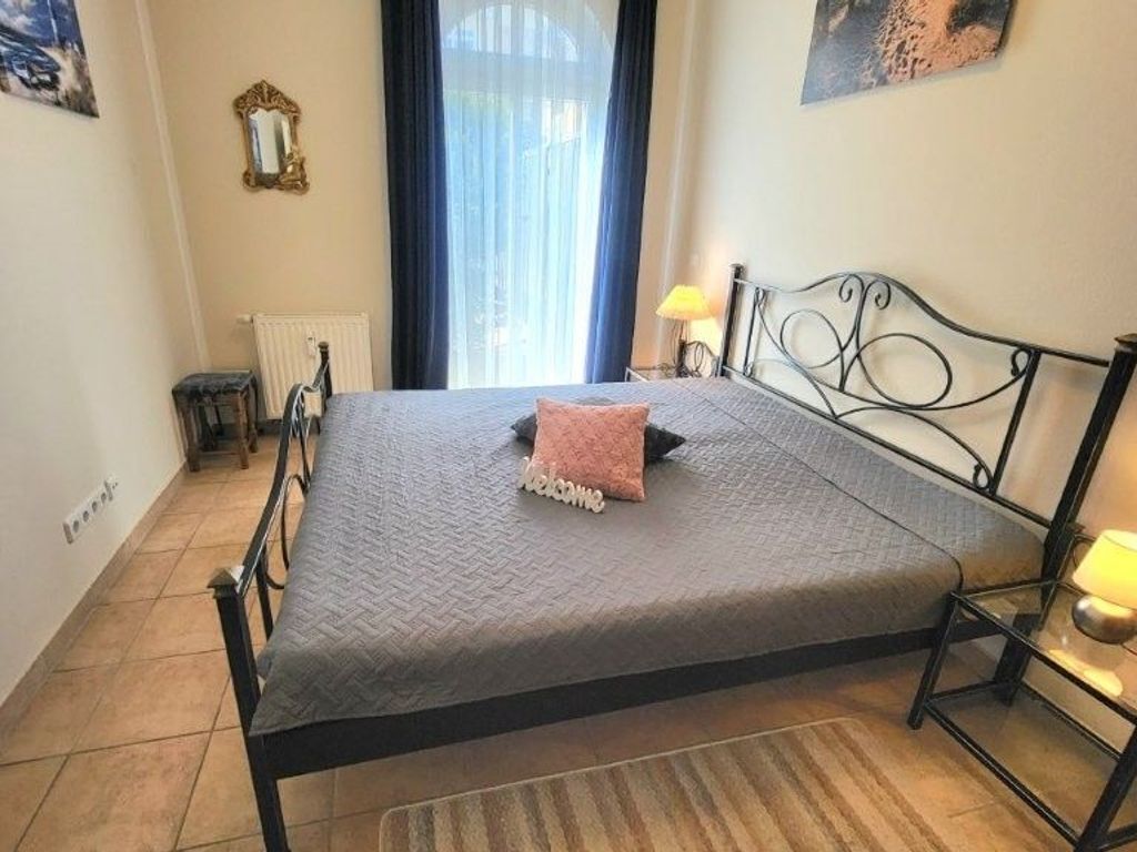 A neatly made bed with a 'welcome' pillow, a bedside lamp, and a window with curtains.