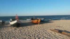 Une plage avec deux bateaux, l’un blanc et l’autre orange, sur le sable.