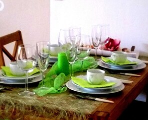 Une table à manger dressée avec des assiettes, des verres et des couverts.