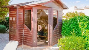 Una pequeña cabaña de madera con techo inclinado, puerta de cristal y espacio interior visible.