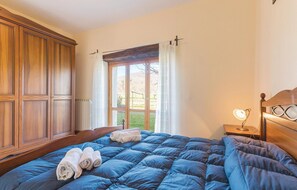 A bedroom with a large wooden wardrobe, a bed with blue bedding, a bedside table with a lamp, and a window with curtains. - Awesome apartment in Pietraviva AR (Pietraviva AR)
