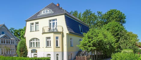 A two-story house with a balcony, a driveway, and a well-maintained garden.