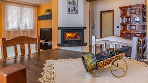 Una sala de estar acogedora con chimenea, una mesa de comedor y una lámpara decorativa.