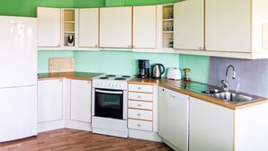 A compact kitchen with white cabinets, a stove, a sink, and a coffee maker. - Lovely home in Sveio with WiFi (Sveio)