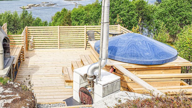 A wooden deck with a sauna, a statue, and a view of a lake and boats. - Lovely home in Sveio with WiFi (Sveio)