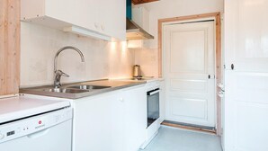 A modern kitchen with white cabinetry, stainless steel appliances, and a wooden ceiling.