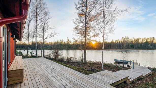 A wooden deck with a view of a lake and trees.