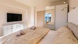 Une chambre d’hôtel moderne dotée d’un grand lit, d’un téléviseur à écran plat, d’une table de chevet et d’un miroir qui reflète la pièce.