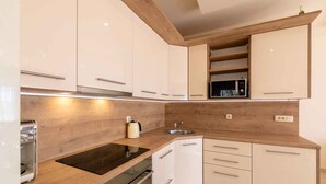 Une cuisine moderne avec des armoires blanches, un plan de travail en bois et des appareils électroménagers intégrés.