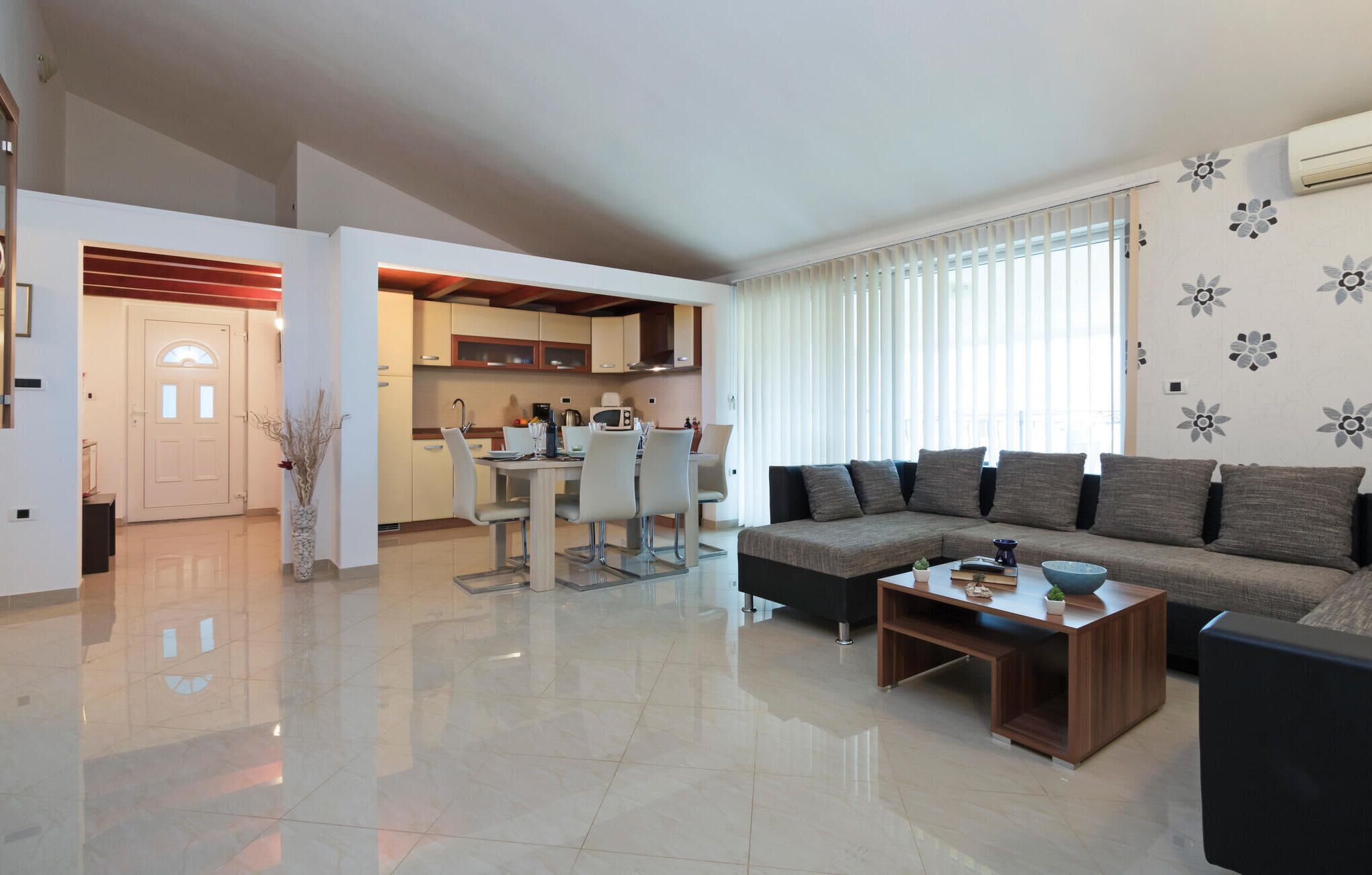 Una sala de estar moderna con un sofá, una mesa de centro y un comedor con sillas, con una cocina al fondo.