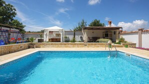 A swimming pool with a stone wall, a covered seating area, and a play structure.