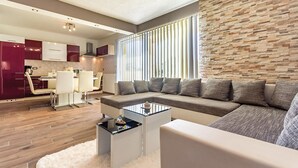 A modern living room with a sectional sofa, a glass coffee table, and a white shag rug.