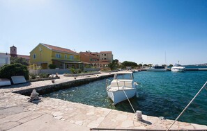 A marina with boats docked, a stone-paved waterfront, and colorful buildings in the background. - Stunning apartment in Sibenik with house sea view (Sibenik)