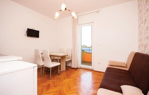 A modern living room with a brown sofa, a dining area with a table and chairs, and a view of the sea through a glass door. - Stunning apartment in Sibenik with house sea view (Sibenik)