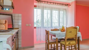 A dining area with a table set for two, a window with sheer curtains, and a kitchen area with a coffee machine. - Amazing apartment in Vrsar with WiFi (Vrsar)