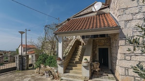 A stone building with a tiled roof, a staircase leading to a door, and outdoor plants. - Amazing apartment in Vrsar with WiFi (Vrsar)