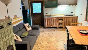 Een gezellige keuken met houten kastjes, een eettafel en een grijze bank met decoratieve kussens.