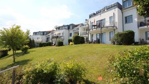 A row of modern multi-story residential buildings with balconies, a well-maintained lawn, and surrounding greenery. - Whg.14, 2nd floor, 2-room, Zinnowitz - Residence Bellevue Fewos Arts - Fewo.cc (Zinnowitz)