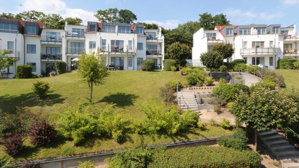 A multi-story residential building with balconies, a grassy courtyard, and a staircase leading to the upper floors. - Whg.14, 2nd floor, 2-room, Zinnowitz - Residence Bellevue Fewos Arts - Fewo.cc (Zinnowitz)