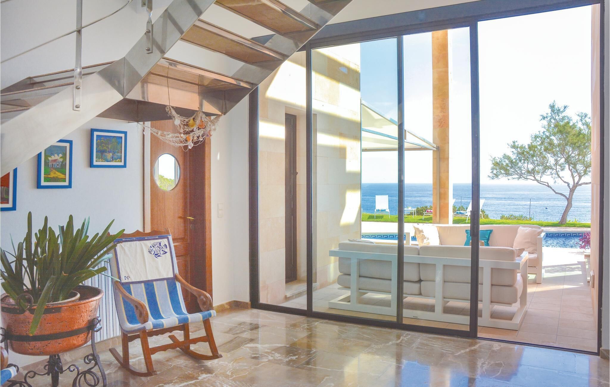 Un interior modern amb una gran porta corredissa de vidre que dona a un balcó amb vista al mar.