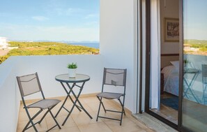 A balcony with two chairs and a small table, a potted plant, and a view of the landscape. - Gorgeous home in Porto Colom (Porto Colom)