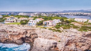 A coastal residential area with modern houses, rocky cliffs, and a marina with boats. - Gorgeous home in Porto Colom (Porto Colom)